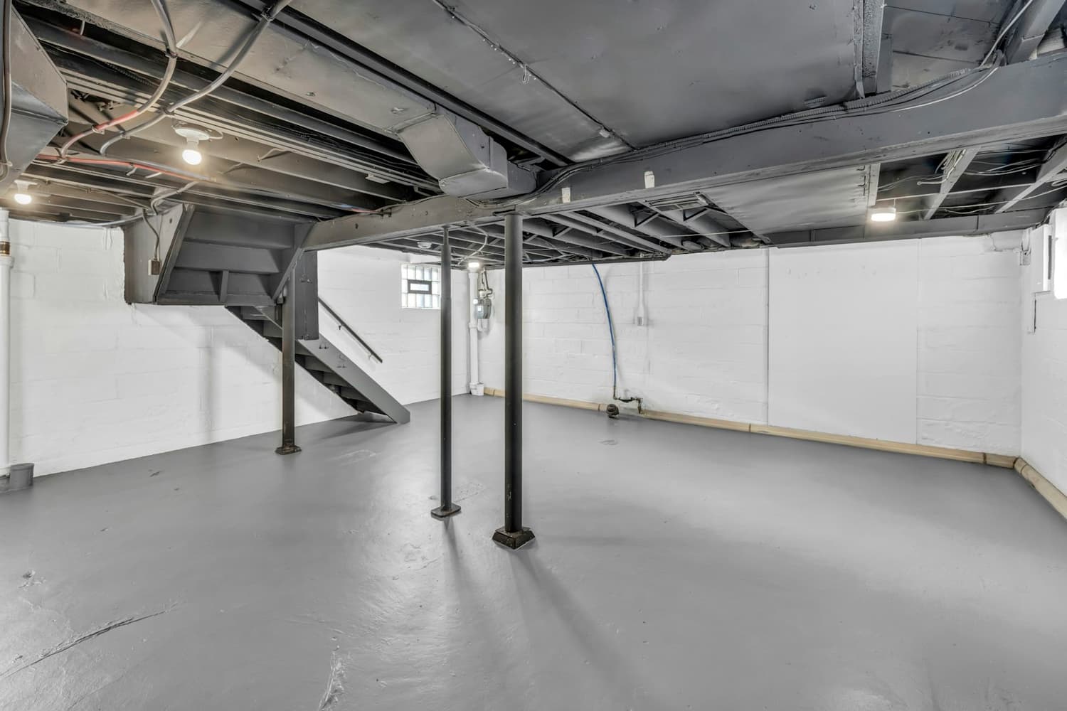 Unfinished basement with a gray epoxy coated concrete floor